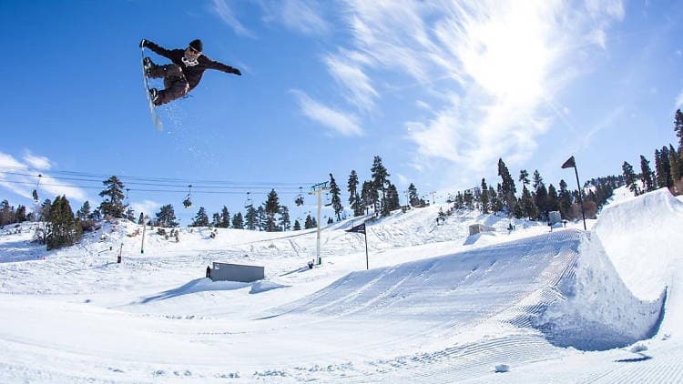 A snowboarder catching big air off a kicker against a blue sky