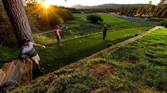 Golfers on the tee at sunset, fairway and the San Bernardino Mountains beyond