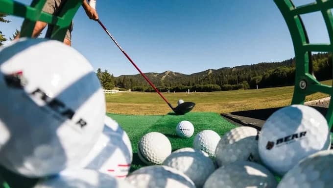 A driver at address on the 300-yard driving range, basket of Bear Mountain range balls in the foreground