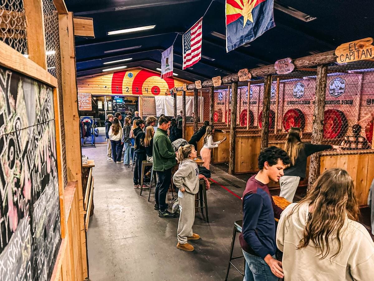 The throwing lanes at Yosemite Axe Throwing — timber posts, log targets, and mountain-named lanes busy with throwers