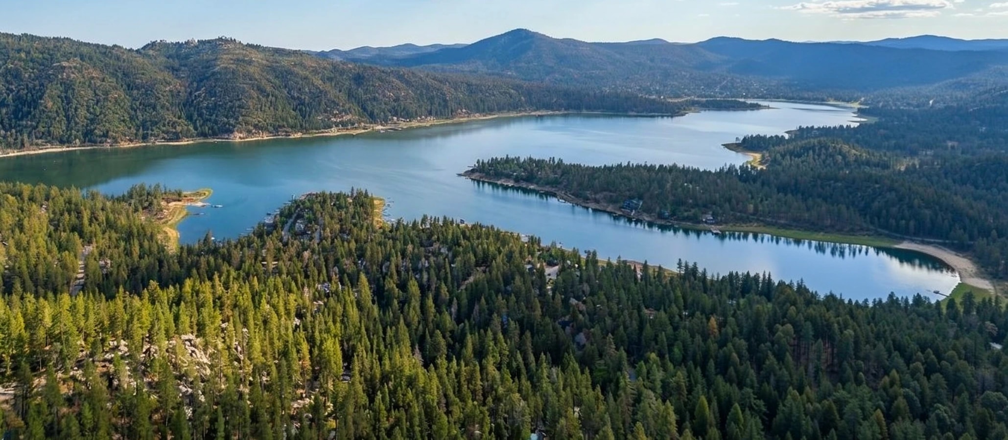 Big Bear Lake from the air, forested slopes running down to the coves with ridgelines beyond